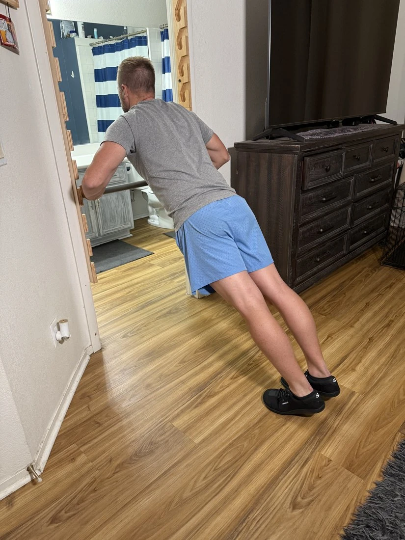 Original rear-angle photograph showing the Primal Tower rail cutouts and bar at medium height during an incline push-up